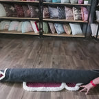 Person unrolling a plush luxury rose carpet with a white 3D border in a home decor setting.